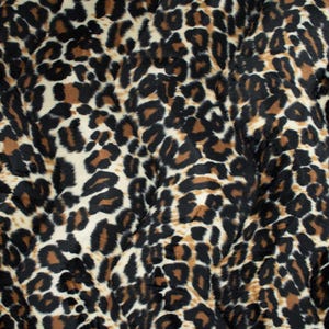 Könnte beinhalten: Nahaufnahme eines Stoffes mit Leopardenmuster. Das Design zeigt schwarze, braune und beige Flecken auf cremefarbenem Hintergrund. Der Stoff hat ein weiches, strukturiertes Aussehen.