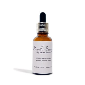 May include: A brown glass bottle of Dovella Beauty Signature Serum with a black dropper and silver collar. The label includes text: "With EGF & Multi-Peptides, Nourish, Hydrate, Vitalize." The bottle contains 1 fl oz (30 ml).