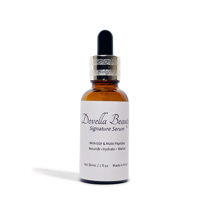 May include: A brown glass bottle of Dovella Beauty Signature Serum with a black dropper and silver collar. The label includes text: "With EGF & Multi-Peptides, Nourish, Hydrate, Vitalize." The bottle contains 1 fl oz (30 ml).