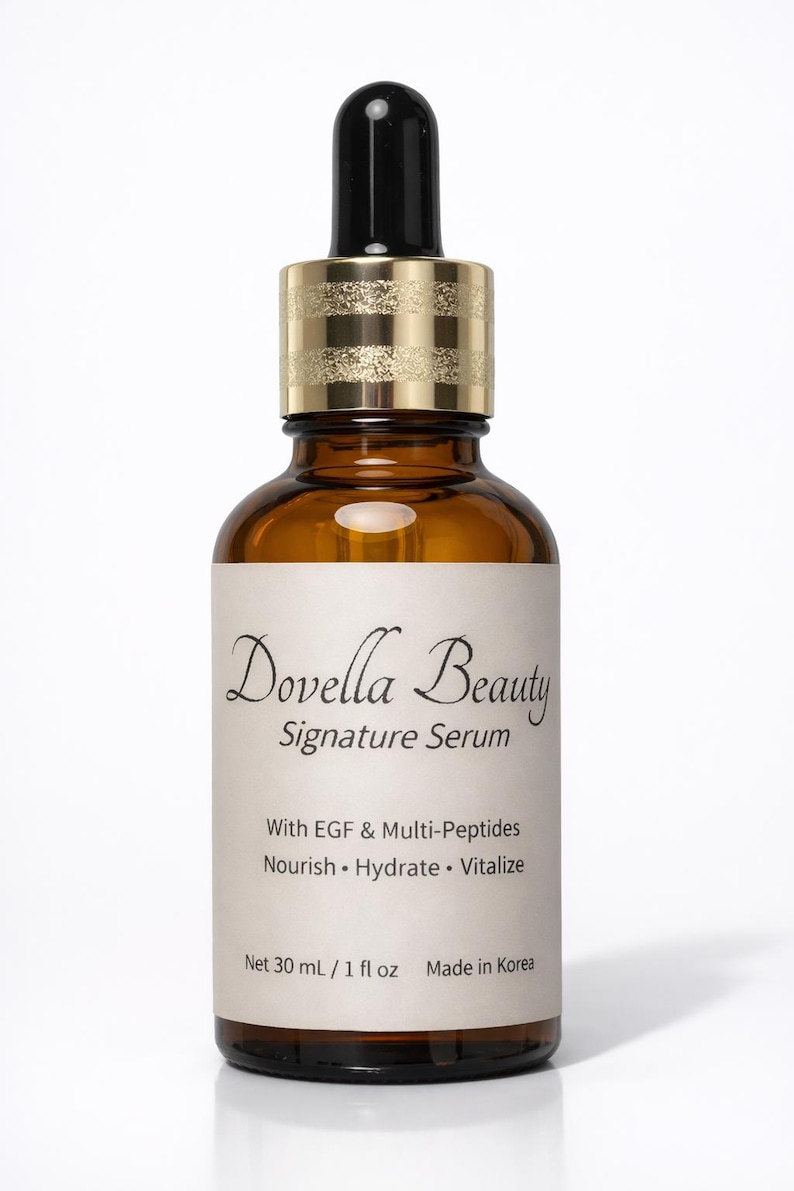 May include: A brown glass bottle of Dovella Beauty Signature Serum with a black dropper and gold-colored cap. The label includes text about the product's ingredients and volume, 1 fl oz.