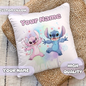 Peut inclure: Coussin blanc personnalisé avec les personnages de dessins animés Stitch et Angel, avec le texte "Your Name". Le coussin a un fond aquarelle avec des accents roses et bleus. Le texte "Custom Pillow" et "High Quality" sont également visibles.