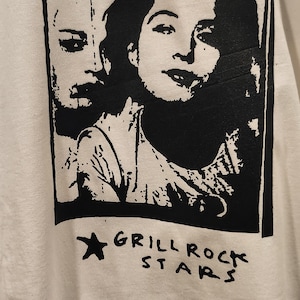 May include: White t-shirt with a black and white graphic. The print shows two faces, the text "Wine. Somethins 1994", and the words "Grill Rock Stars" with a star. The shirt has a round neck.