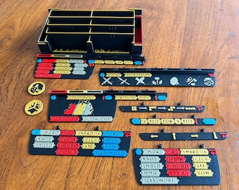 May include: A set of black and gold game pieces for a board game. The pieces include a variety of shapes and sizes, including cards, tokens, and markers. The pieces are labeled with words like "Sword", "Fire", "Ambrosia", "Matred", "Knife", "Spear", "Club", "Whip", "Shield", "Sword", "Axe", "Bow", "Cestus", and "Slab Sword".