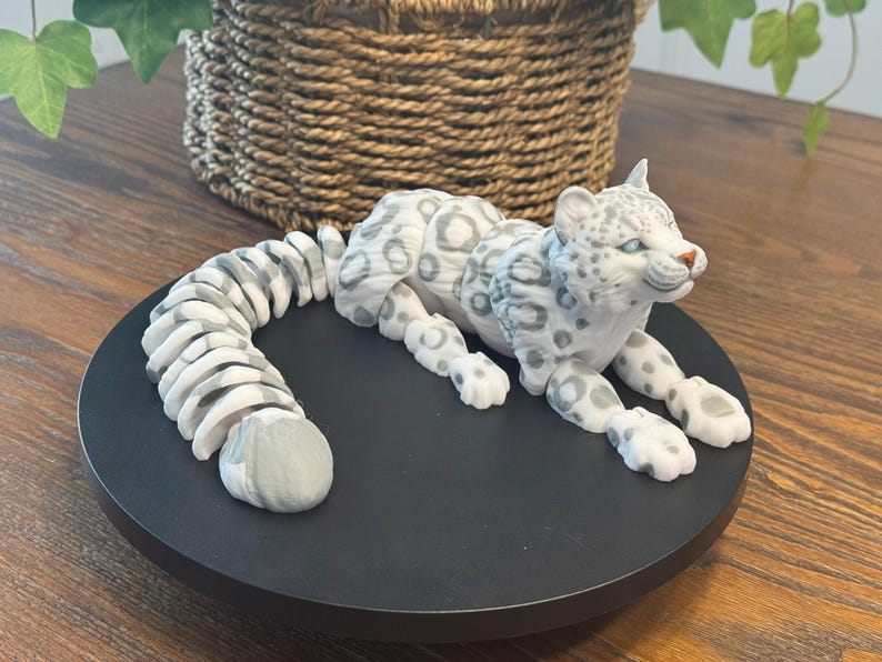 May include: A white and gray snow leopard figurine with a curled tail. The figurine is made of ceramic and has a realistic appearance.