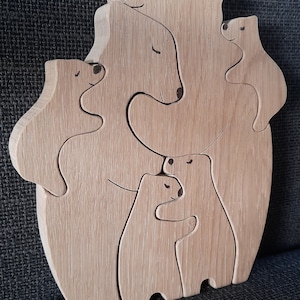 May include: Wooden puzzle of a bear family, with a mother bear, a father bear, and a baby bear. The bears are all carved in a simple style and are interlocking.