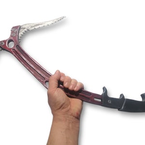 May include: A red and silver ice axe, a tool for mountaineering and ice climbing. The axe features a curved pick, a hammer, and a spike for secure grip on ice and snow. The handle is red, and the head is silver.