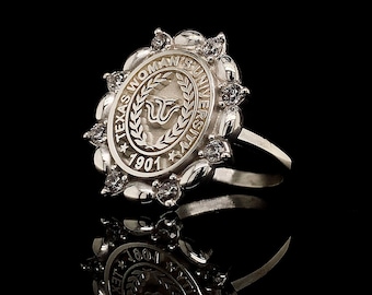 May include: A silver ring with a white oval-shaped stone set in a silver band. The stone has the words "Texas Woman's University 1901" engraved on it.