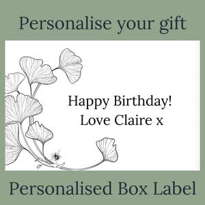 May include: A personalized box label with the text "Happy Birthday! Love Claire x". The label features a black and white illustration of ginkgo leaves and a bee. The words "Personalise your gift" and "Personalised Box Label" are also present.