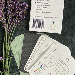 May include: A deck of 39 yoga pose cards with a colorful illustration of a person in a yoga pose on the back of the box. The box has a white background with black text that reads "Create your own yoga routine! This yoga deck has 39 beautiful cards which include: yoga pose picture, common name, Sanskrit name, pose description, health benefit, chakras, inspirational quote. etsy.com/uk/shop/GaiaAsana".