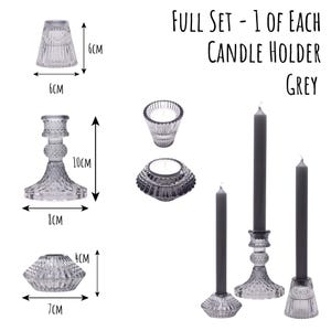 May include: A full set of grey glass candle holders and candles. The set includes a variety of holders, including a 10cm tall candlestick and a 6cm tall holder. The text "FULL SET - 1 OF EACH CANDLE HOLDER GREY" is displayed.