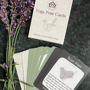 May include: A deck of yoga pose cards with a green and black design. The card shown features a line drawing of a person in the boat pose, with the name of the pose, "Boat Pose", and the Sanskrit name, "navasana", printed in black text. The card also includes instructions for the pose and a description of its benefits, "toning, strengthening".
