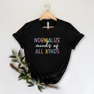 Puede incluir: Camiseta negra con el texto "NORMALIZE minds of ALL KINDS" en colores arcoíris.