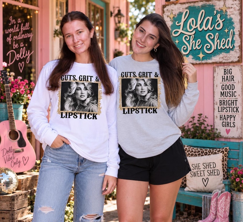 May include: A white long-sleeve shirt and a light grey long-sleeve shirt, both featuring a black and white photographic print of a woman with blonde hair, surrounded by a gold glitter border and the text GUTS, GRIT & LIPSTICK in black.