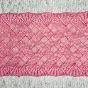 Pode incluir: Borda de renda rosa com um padrão tecido e bordas onduladas. A renda apresenta um design geométrico repetitivo, com uma trama delicada e aberta. A borda é de um tom rosa vibrante, adequada para vários projetos de artesanato.