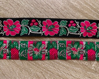 Puede incluir: Dos tiras de adorno con diseños florales. La tira superior es negra con flores rosas y hojas plateadas. La tira inferior es verde, rosa y plateada con un patrón geométrico.