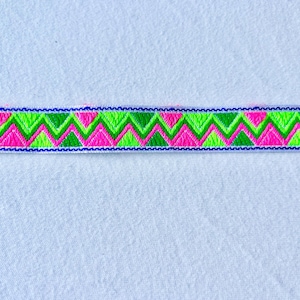 May include: A close-up of a pink, green and blue patterned trim. The trim has a zig-zag pattern.
