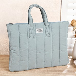 May include: A light blue quilted laptop bag with a zipper closure and a small rectangular label with the text "JAPANESE STYLE" on the front.
