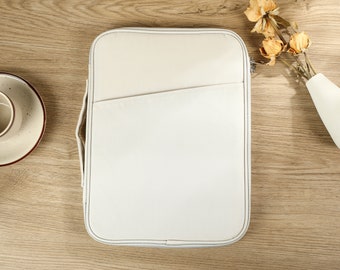 May include: A white canvas zippered laptop sleeve with a front pocket.