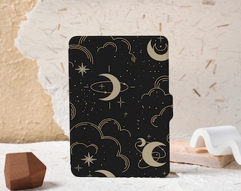 May include: A black e-reader cover with a gold celestial pattern featuring moons, stars, and clouds.