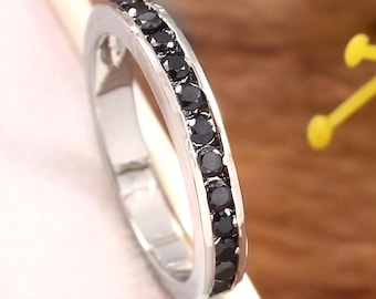 May include: A silver band ring with a row of black gemstones around the entire band.