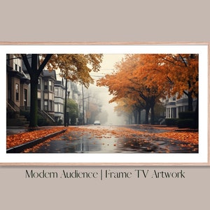 Op de afbeelding: Een mistige straat met bomen in herfstkleuren. De bladeren vallen van de bomen en bedekken het natte trottoir. De huizen in de straat zijn zichtbaar op de achtergrond.
