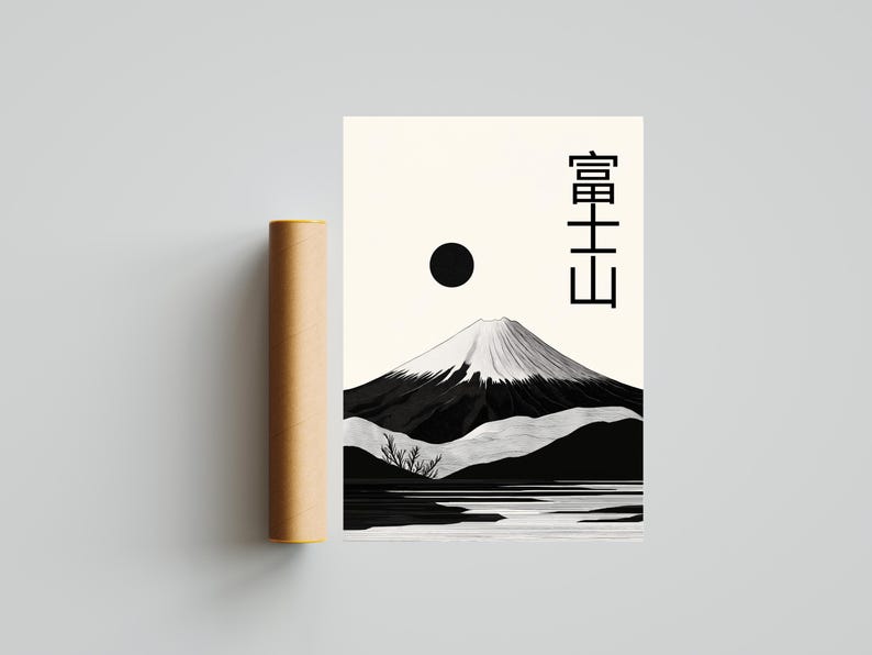 May include: A black and white minimalist art print featuring Mount Fuji with a snow-capped peak, a black sun, and Japanese text. A brown cylindrical tube is next to the print. The artwork is on a cream-colored background.