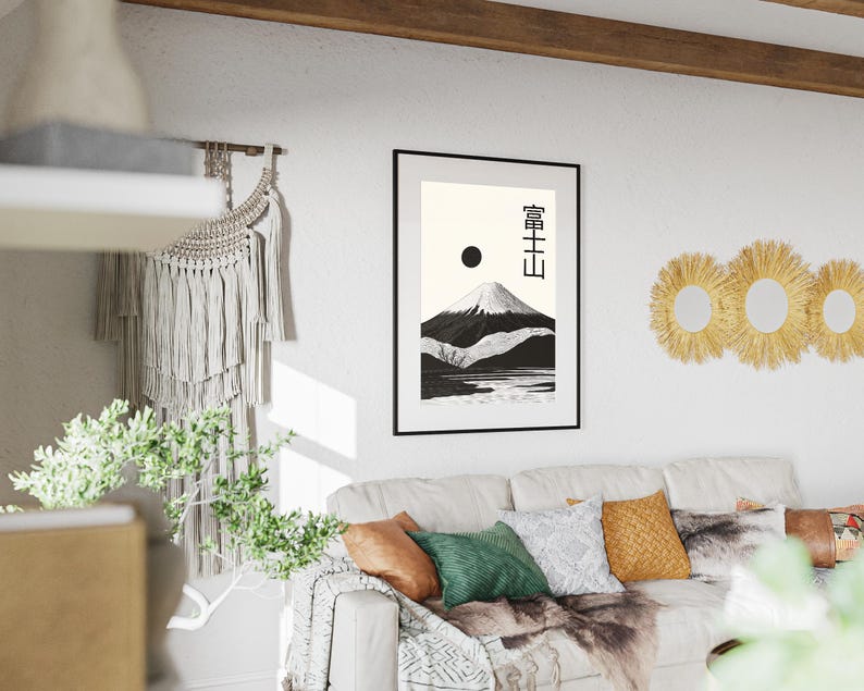 May include: A framed black and white print of a mountain landscape with Japanese text. The artwork depicts a snow-capped mountain, a lake, and a black sun against a cream background. The print is displayed above a white sofa with colorful pillows.