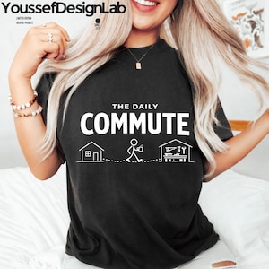 May include: Black t-shirt with the text "THE DAILY COMMUTE" in white, along with a graphic of a house, a stick figure, and a workshop. The shirt also features the brand name "YoussefDesignLab" at the top left.