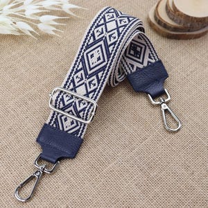 Peut inclure: Une sangle tissée à motifs bleus et blancs avec des fermoirs en métal argenté. La sangle est en tissu et en cuir.