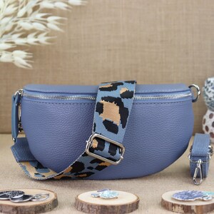 Può includere: Una marsupio in pelle blu con chiusura a zip e una tracolla regolabile con stampa leopardata.