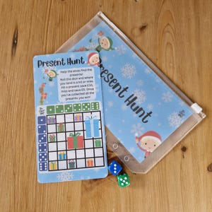 May include: A blue and white game board with the text "Present Hunt" and a grid of presents. The game includes two dice and instructions to help elves find presents.