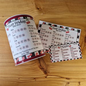 May include: A cylindrical calendar with a cherry design and the text "Fiver Friday 2026 Edition." Several rectangular calendars with the same design are also present. The calendars display dates for various months.