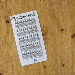 May include: A white sheet with the text "Tattoo Fund" at the top. The sheet is filled with black and white drawings of tattoo ink bottles. At the bottom of the sheet, there is a black and white drawing of a single tattoo ink bottle with an equals sign next to it.