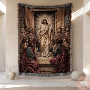 May include: Woven tapestry depicting a religious scene. A central figure in white robes, arms raised, is surrounded by figures in robes. The artwork shows a doorway with open doors, and light radiating from behind the central figure. The tapestry has a fringed border.