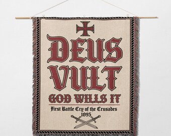May include: Woven wall hanging with the text "DEUS VULT GOD WILLS IT" in burgundy lettering. Features a cross at the top and crossed swords at the bottom. The banner is beige with a black and burgundy border.