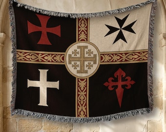 May include: A woven throw blanket featuring a black and cream background divided by a central gold and red ornate cross pattern. The four quadrants display a red cross, a black Maltese cross, a white cross, and a red cross of Santiago.