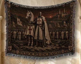 May include: A rectangular woven tapestry featuring a knight in armor standing beside a horse, both adorned with red cross emblems. The scene includes a large army with shields, a distant castle, and a dark sky. The border has a fringed edge.
