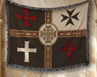 May include: A woven throw blanket featuring a dark brown and cream background divided into quadrants. It displays a red cross, a black Maltese cross, a white cross, and a red cross of Santiago, with a central Jerusalem cross and fringed edges.