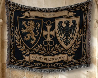 May include: A woven throw blanket featuring a black and tan design with two heraldic shields, one displaying a lion and the other an eagle. A central cross, laurel leaves, and banners with the text EST. 2021 and FAMILY BLACKWOOD are included.