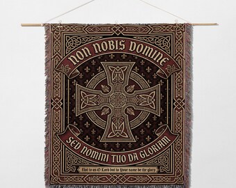 May include: A tapestry wall hanging with a burgundy and gold Celtic cross design. The text "non nobis domine" and "sed nomini tuo da gloriam" are displayed on the tapestry. The bottom of the tapestry reads "Not to us O Lord but to Your name be the glory."