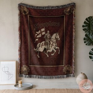 May include: Burgundy tapestry throw blanket featuring a knight on horseback with a flag, and the word "Templars". The design is in cream and brown tones, with a decorative border and fringe.