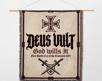 May include: A beige tapestry banner with a dark red cross at the top and the words "DEUS VULT" in gothic lettering. Below, it reads "God wills It" and "First Battle Cry of the Crusades 1095". Two crossed swords are at the bottom.