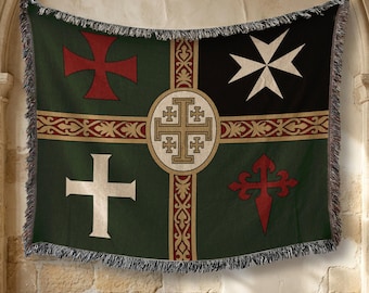May include: A woven throw blanket featuring a dark green background with a central gold cross emblem. The design includes four distinct symbols: a red cross, a white Maltese cross, a white Latin cross, and a red cross of Santiago with fringe.