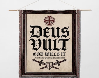 May include: Woven wall hanging with the text "DEUS VULT" in large black gothic lettering, with "GOD WILLS IT" below. Features a cross and swords design, with a decorative border and fringe.