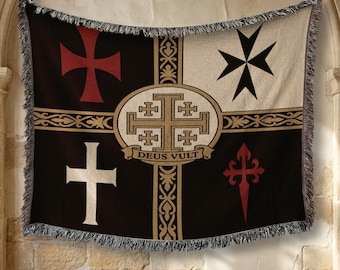 May include: A woven throw blanket featuring a dark background divided into quadrants with various cross symbols, including a red Templar cross, a white Latin cross, a black Maltese cross, and a red cross of Santiago, with a central Jerusalem cross and the text DEUS VULT.