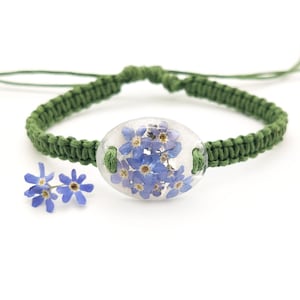 Green macrame braided bracelet with natural plants. Resin bracelet with dried forget me nots. Terrarium bracelet with natural blue flowers.