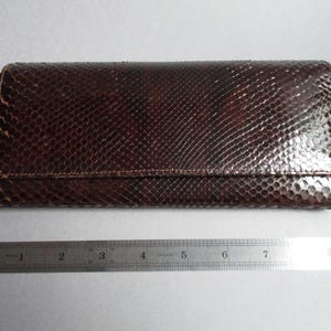 Peut inclure: Un portefeuille en cuir de serpent brun avec une fermeture à rabat. Le portefeuille mesure environ 18 cm de long.