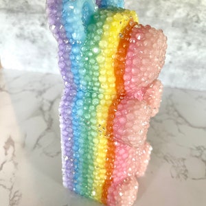 Pu&ograve; includere: Un orso gommoso arcobaleno con una finitura scintillante. L'orso &egrave; fatto di plastica trasparente e ha un motivo arcobaleno.