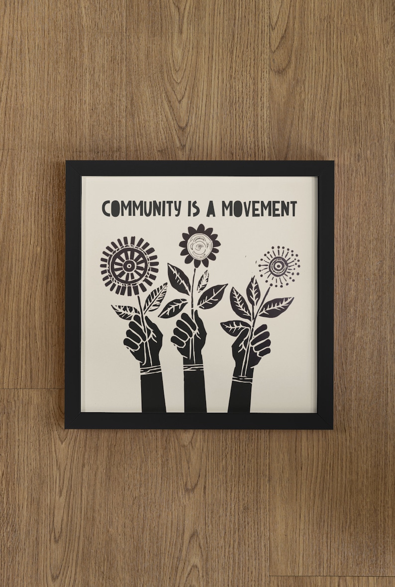May include: Black and white framed print with the text "COMMUNITY IS A MOVEMENT" and three stylized black flowers with stems and leaves.