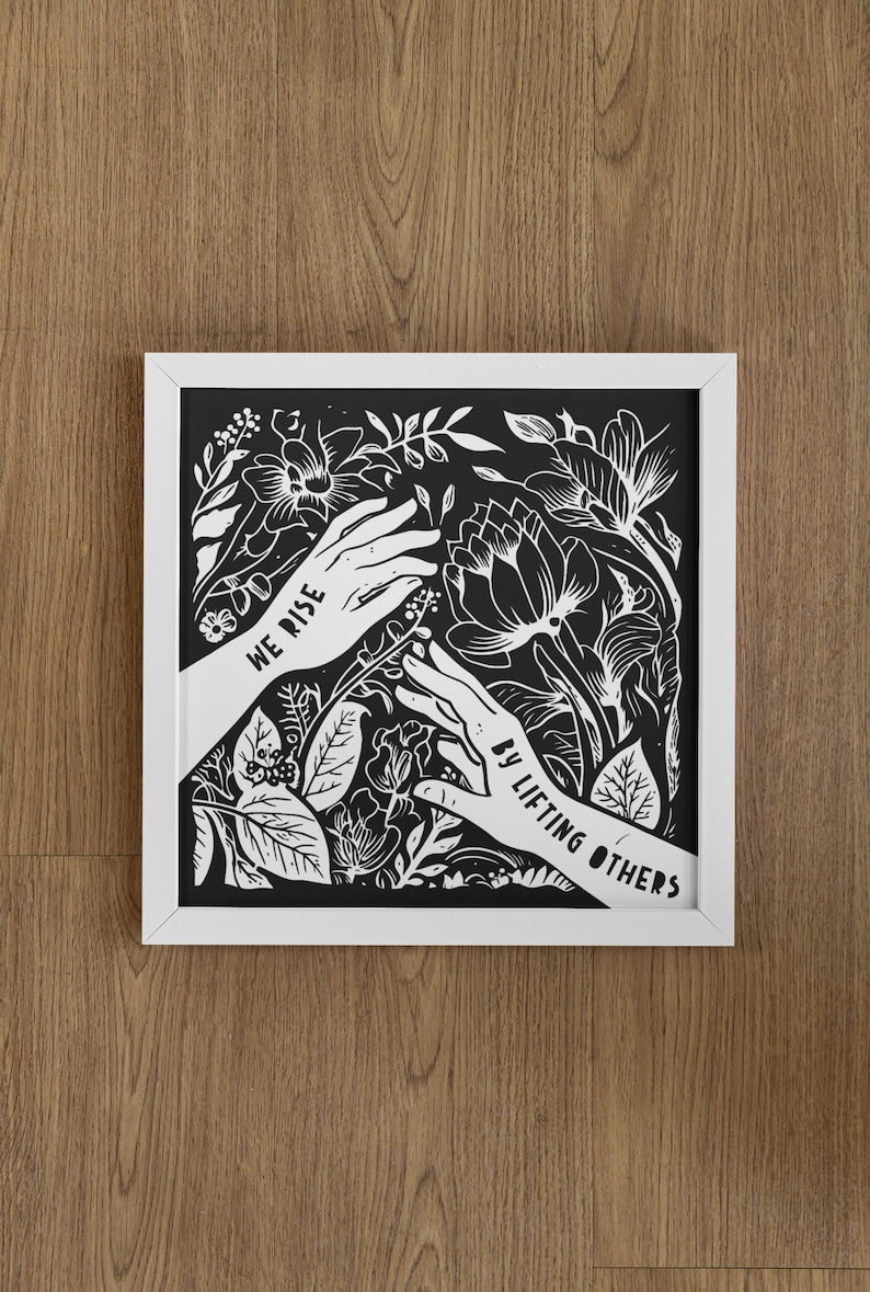 May include: Black and white framed print with a floral design and the text "We rise by lifting others".